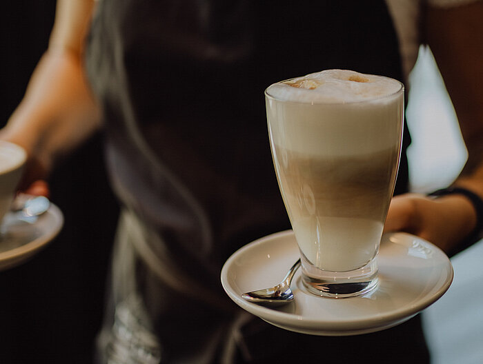 A member of staff carrying two cups of coffee at the Gourmet & Wellness Hotel Lürzerhof