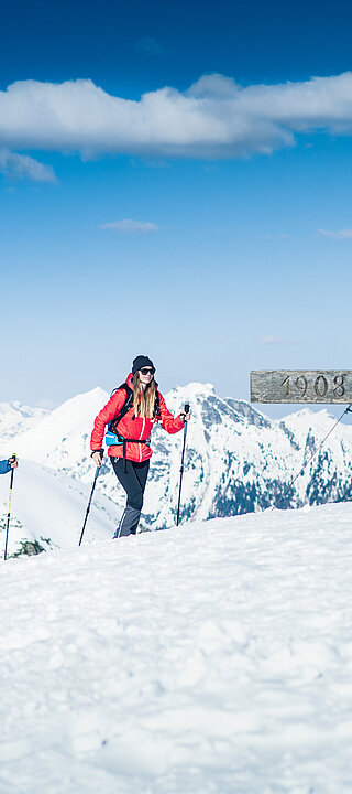 Two ski tourers at the summit cross with panoramic views of the snow-covered Alps in Obertauern