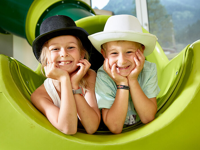 Two children play on a slide in the play area of the Lürzerhof, the family hotel in Austria for vacations with children.