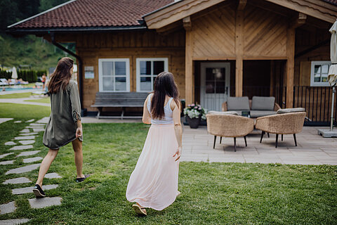 Two women walk relaxed towards a comfortable seat at the Lürzerhof.