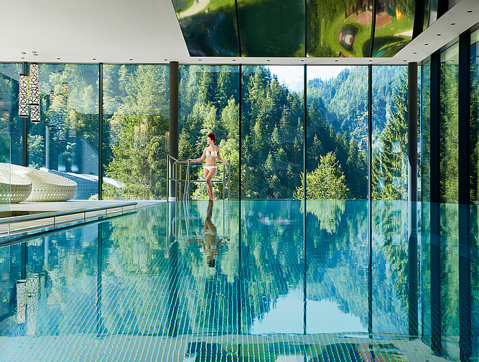 A woman stands next to the indoor pool at the Lürzerhof wellness hotel in Salzburg.