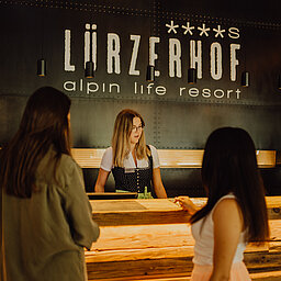 Two women are standing at the reception desk of the Lürzerhof.