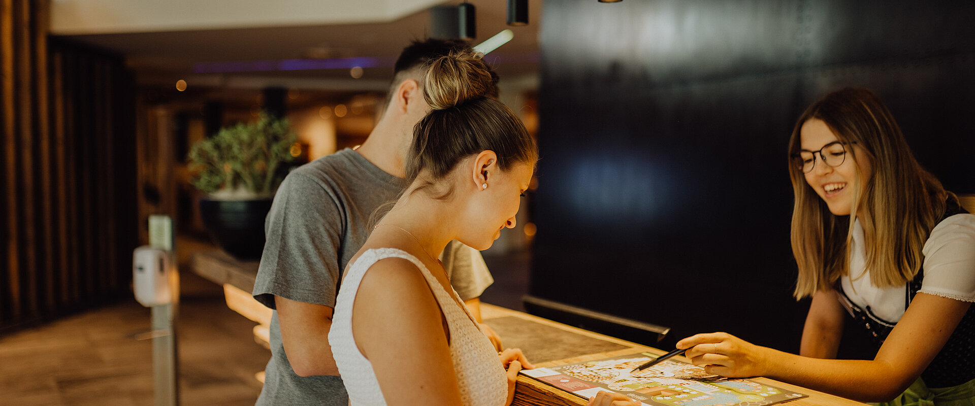 A couple is standing at the reception desk of the Lürzerhof.