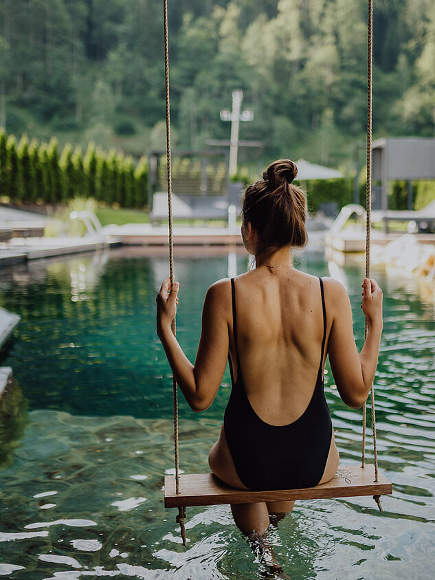 A woman swings on a swing above the natural pool at the Lürzerhof wellness hotel in Salzburg.