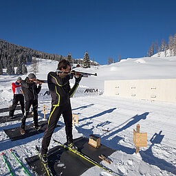 Biathletes aim rifles at a shooting range in the snow