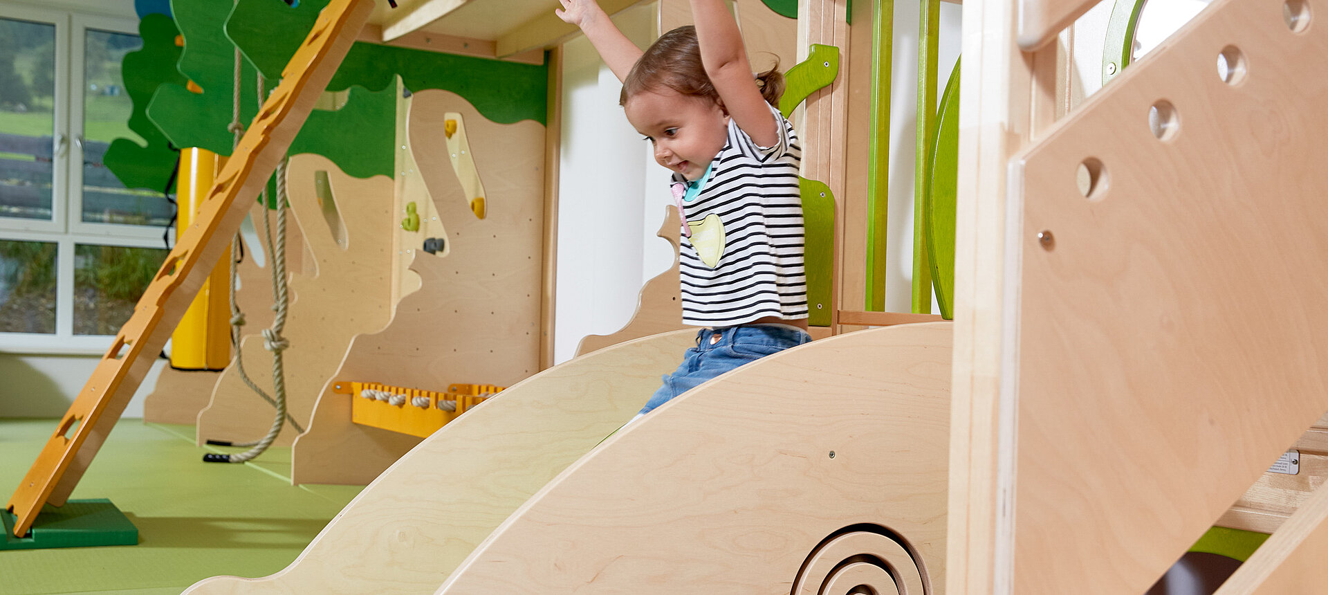 A girl sliding down a slide in the play area at the Lürzerhof, the family hotel in Austria for vacations with children.