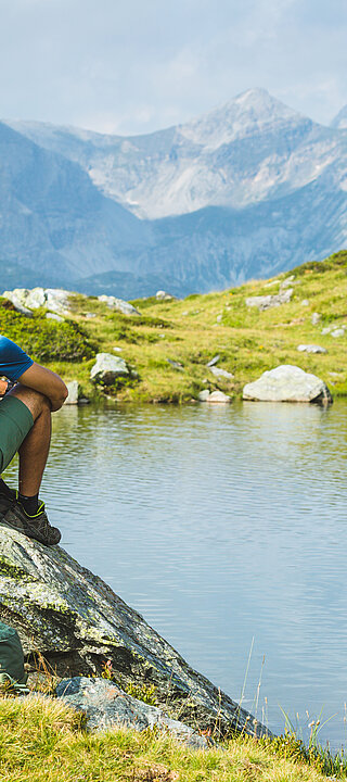 Two hikers sitting on rocks by a mountain lake in Obertauern