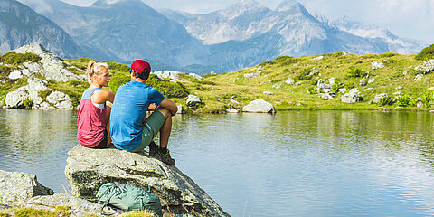 Two hikers sitting on rocks by a mountain lake in Obertauern