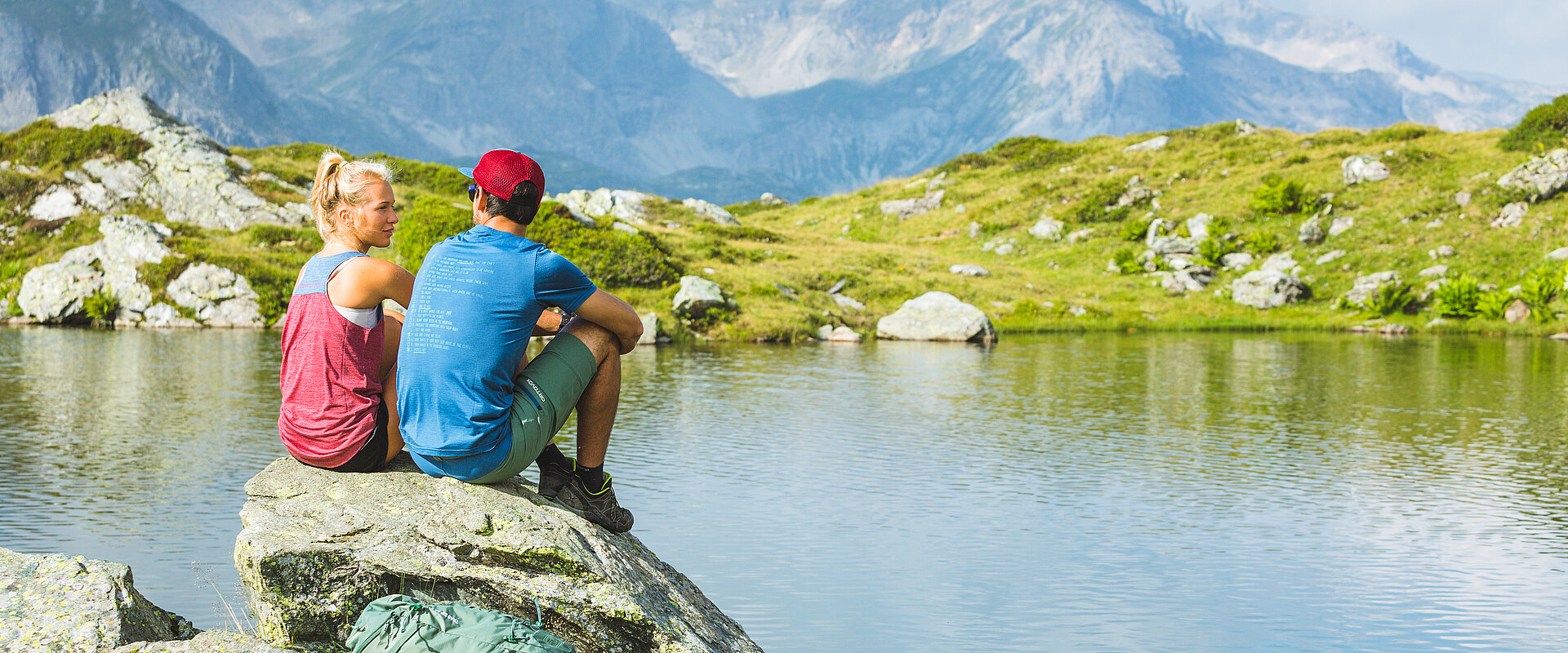 Two hikers sitting on rocks by a mountain lake in Obertauern