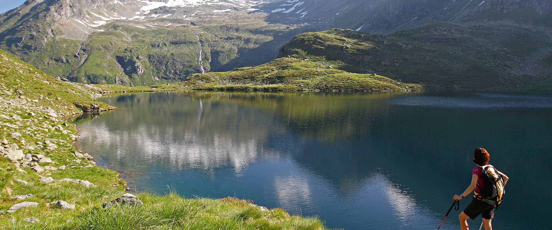 A hiker relaxes with a view of the mountain lake during her active vacation in Austria.