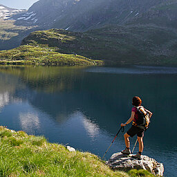 A hiker relaxes with a view of the mountain lake during her active vacation in Austria.