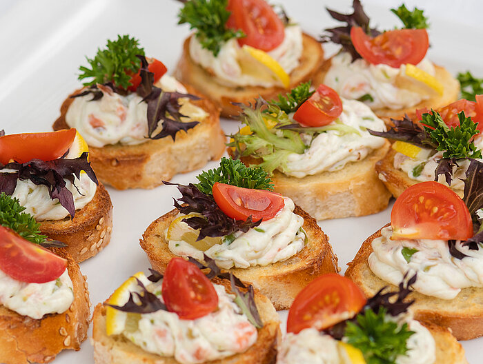 Canapés with cream, tomato, lemon, and herbs on white bread