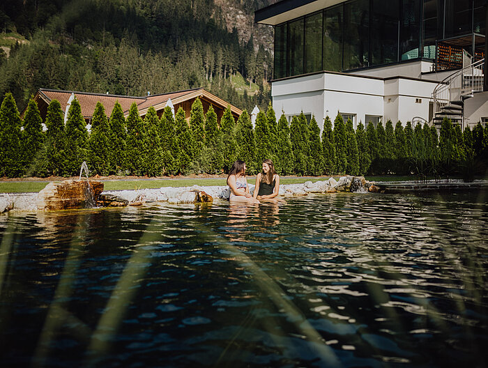 Guests enjoy relaxing by the natural pool in the adults-only area at the Lürzerhof wellness hotel in Salzburg.