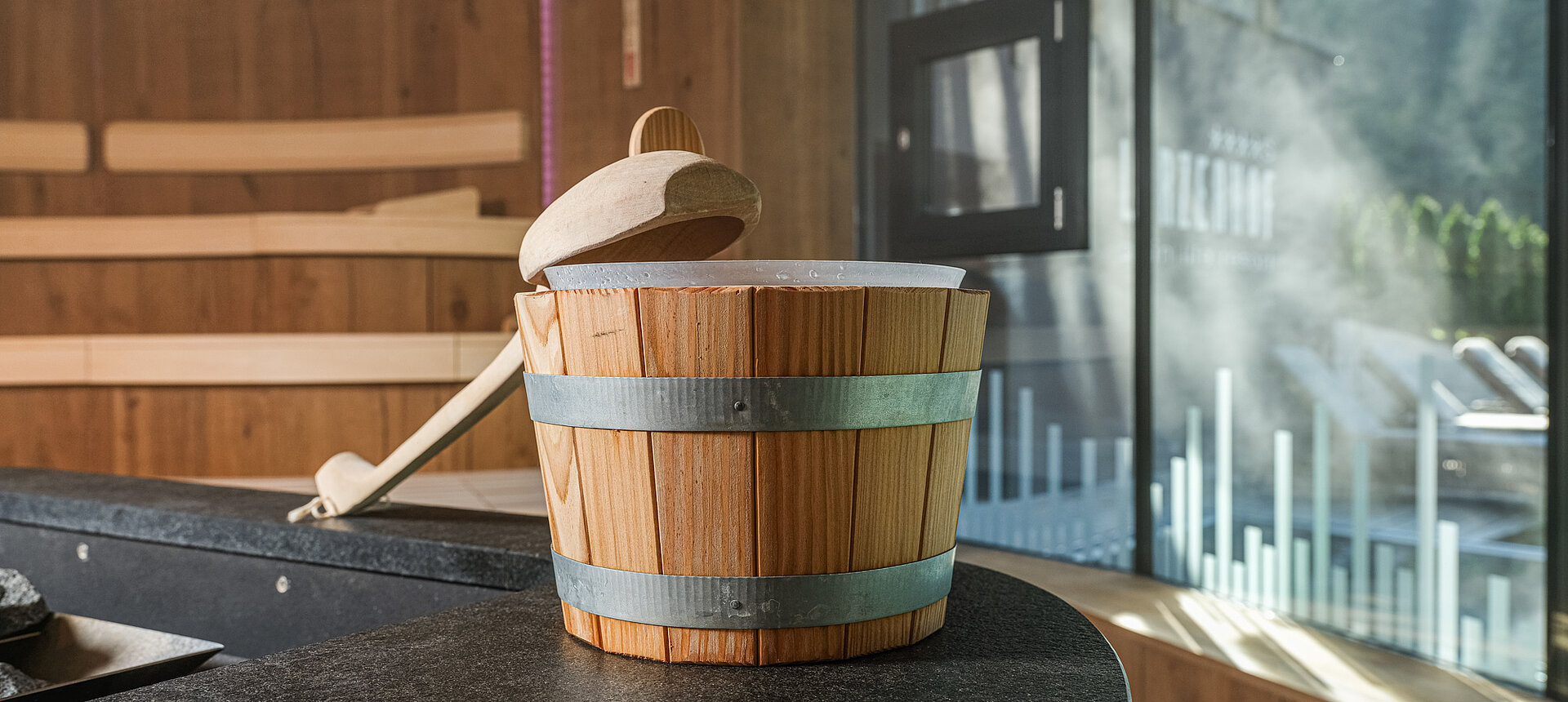 Sauna area at the Lürzerhof wellness hotel in Salzburg with a traditional wooden bucket for pouring water over the sauna stones.