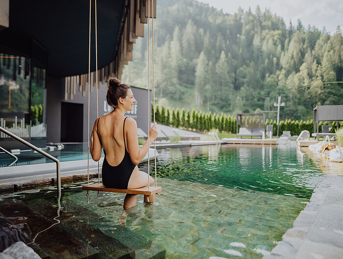 A woman swings over the natural pool in the adults-only area of the Lürzerhof wellness hotel in Salzburg.