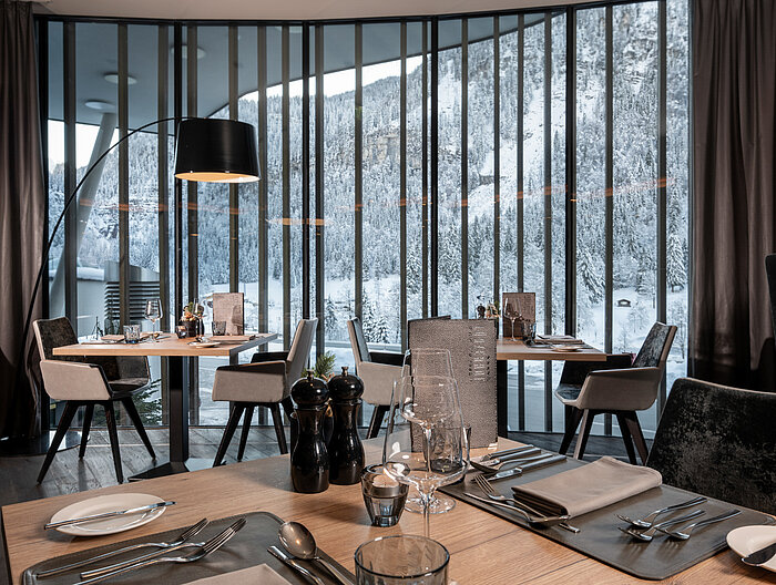 A stylishly decorated restaurant area in the Lürzerhof Gourmet & Wellness Hotel with panoramic views of the snow-covered mountain landscape.