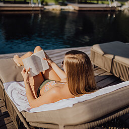 A woman enjoys the sun at the mountain lake pool at the Lürzerhof Wellness Hotel in Salzburg.