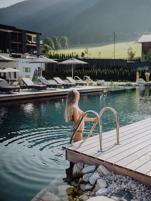 A woman enters the mountain lake pool at the Lürzerhof Wellness Hotel in Salzburg.