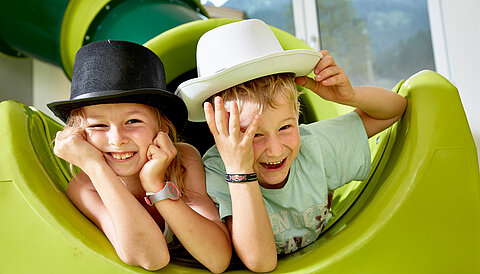 Two children play on a slide in the play area of the Lürzerhof, the family hotel in Austria for vacations with children.