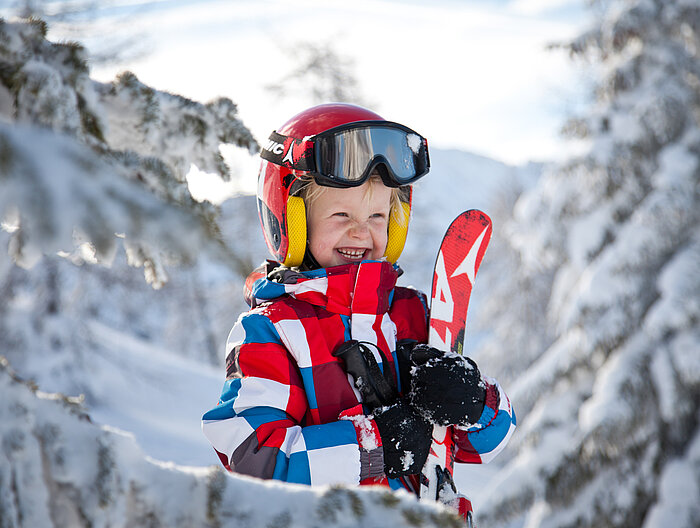 Child with skis in hand on a skiing holiday in Obertauern