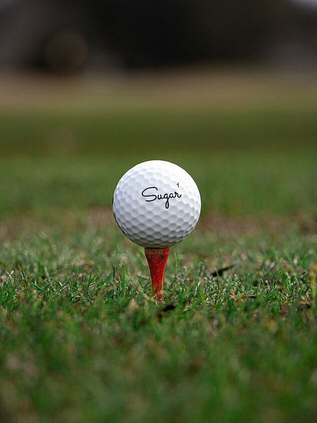 Golf ball on red tee on a golf course