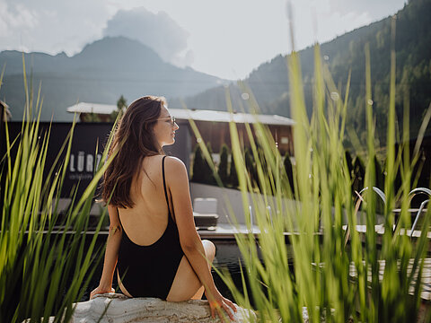 A woman sits by the natural pool in the adults-only area of the Lürzerhof wellness hotel in Salzburg.