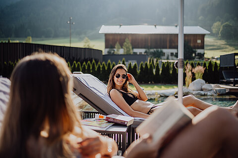 A woman enjoys the sun at the mountain lake pool at the Lürzerhof Wellness Hotel in Salzburg.