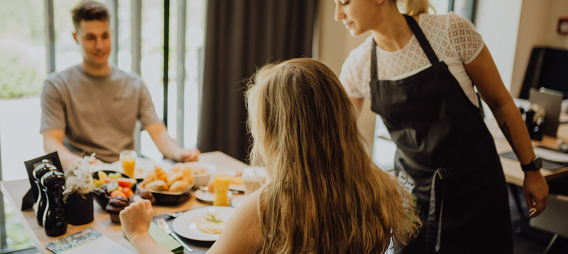 A couple enjoys breakfast at the Lürzerhof Gourmet & Wellness Hotel while being served by a friendly member of staff.