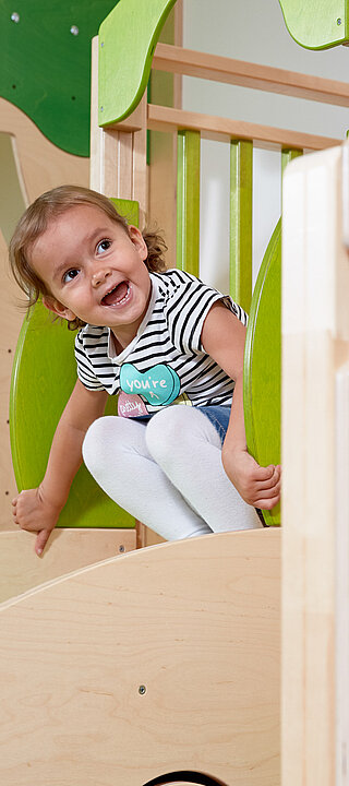 A girl sliding down a slide in the play area at the LÃ¼rzerhof, the family hotel in Austria for vacations with children.