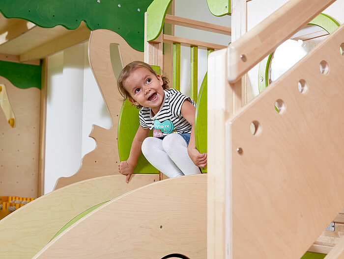 A girl sliding down a slide in the play area at the Lürzerhof, the family hotel in Austria for vacations with children.