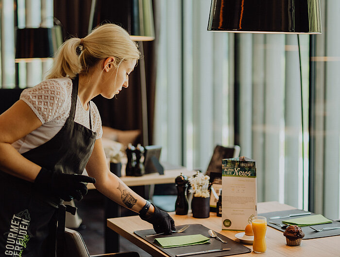 A member of staff carefully prepares a breakfast table at the Lürzerhof Gourmet & Wellness Hotel.