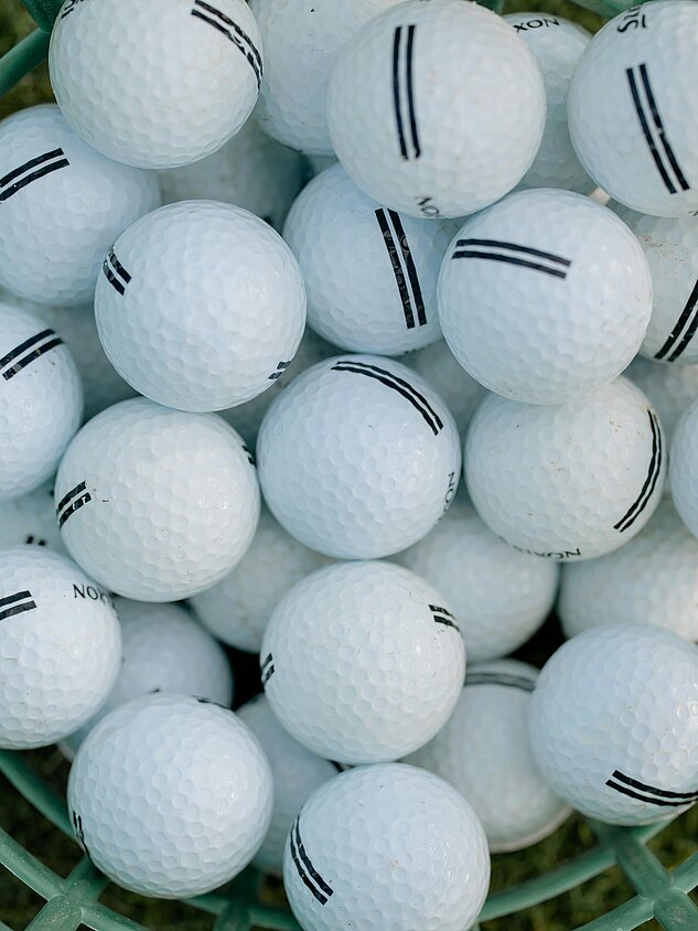 Basket containing numerous white golf balls with black markings