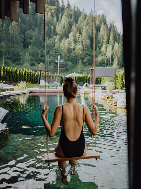 A woman swings on a swing above the natural pool at the Lürzerhof wellness hotel in Salzburg.