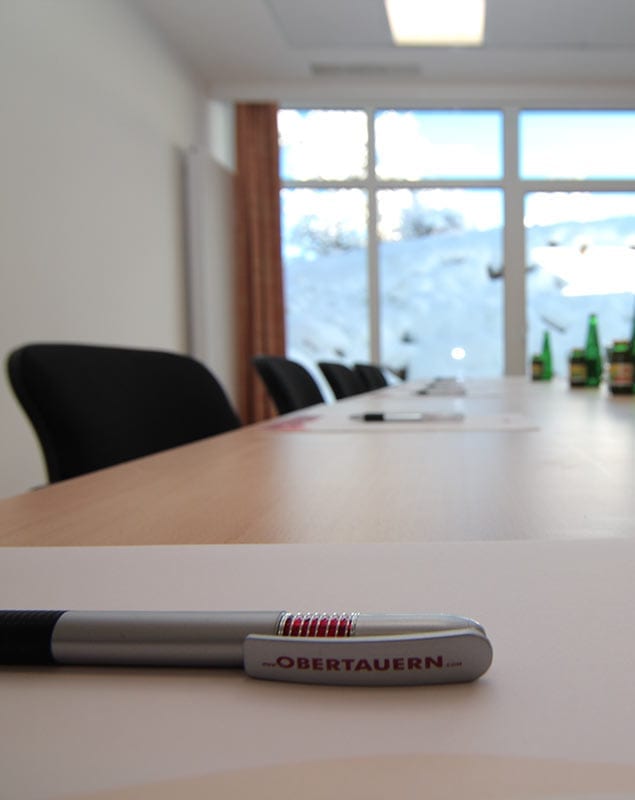 Moderner Seminarraum mit Konferenztisch, Schreibmaterialien und Blick auf verschneite Landschaft im Hotel Lürzerhof